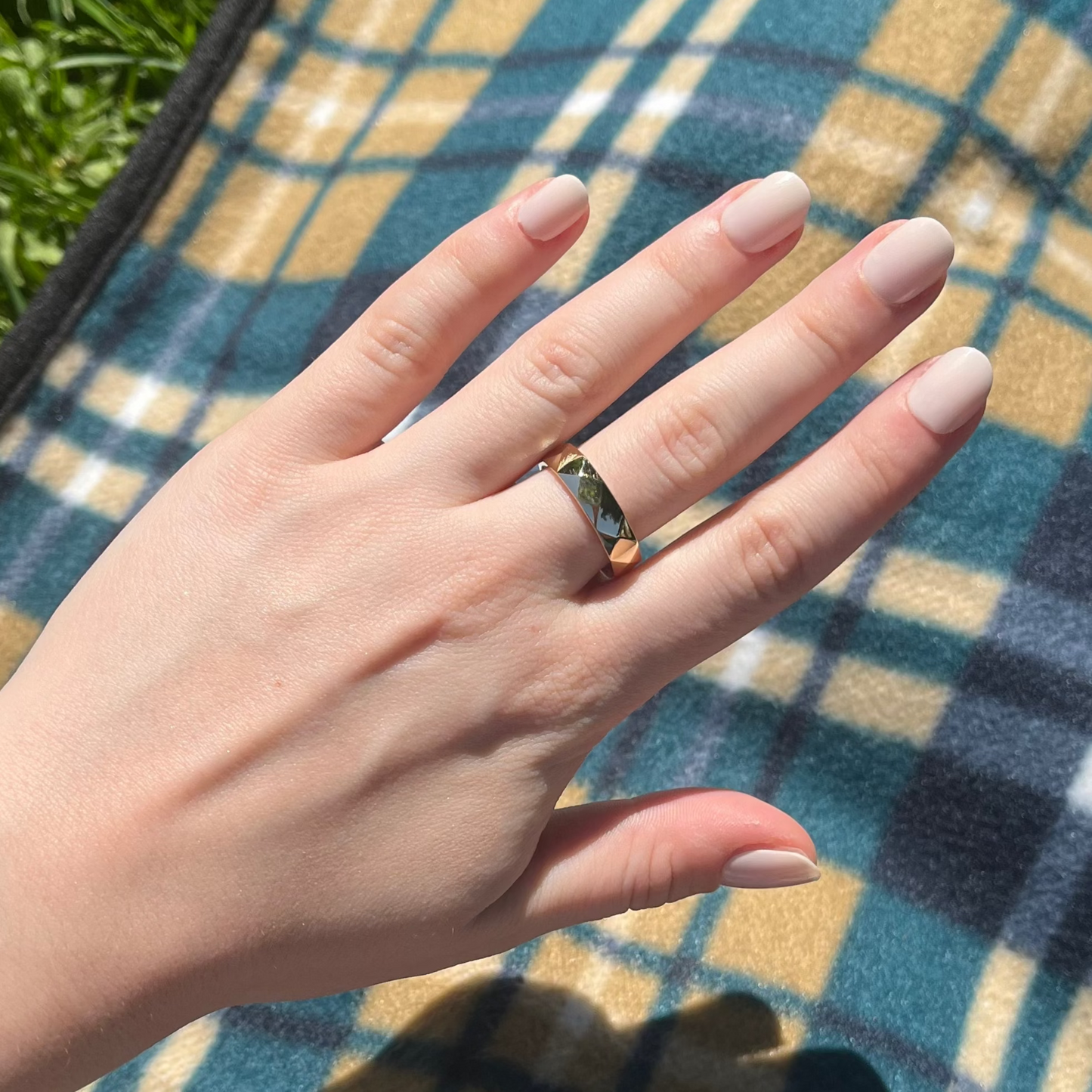 Hand with a ring on a plaid blanket outdoors