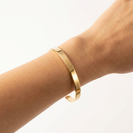 Gold bracelet on a wrist against a white background