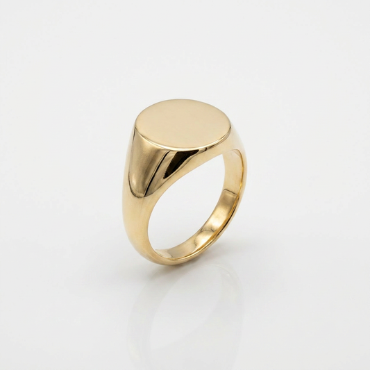 Gold signet ring with a flat, polished top on a light gray background