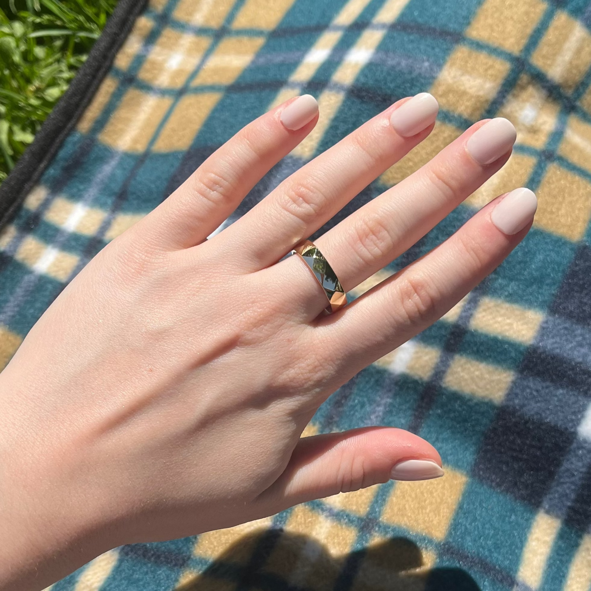 Hand with a ring on a plaid blanket outdoors