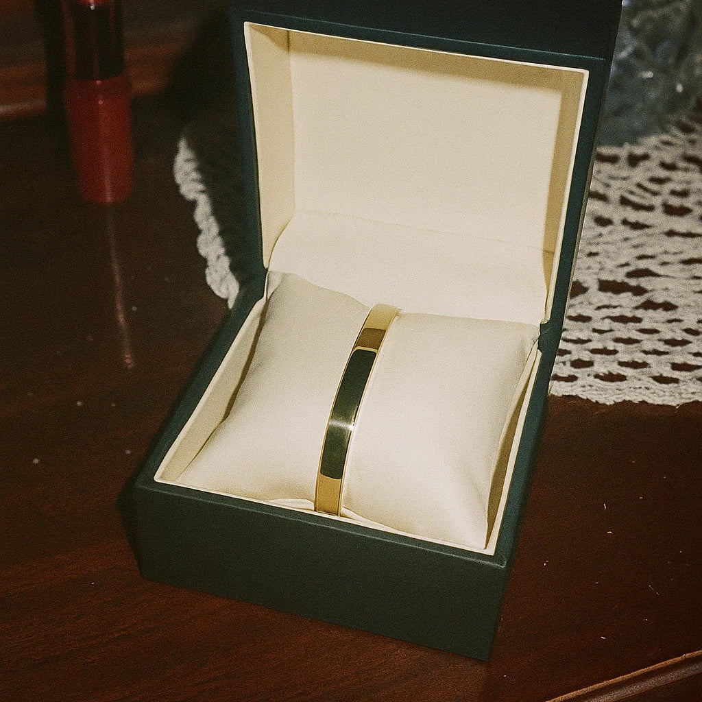 Gold bracelet in an open green box on a wooden surface