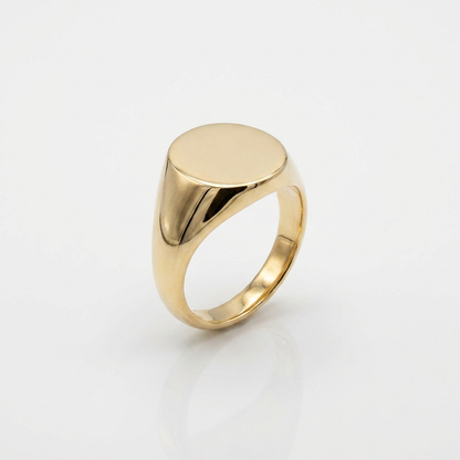 Gold signet ring with a flat, polished top on a light gray background
